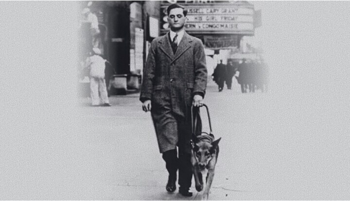 Black-and-white photo of Dr. Mark L. Morris walking alongside his guide dog Buddy on a city street in the 1930s.