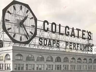 Historic Colgate Clock sign from the 1900s on a building with a sign that reads Colgate's Soaps Perfumes.