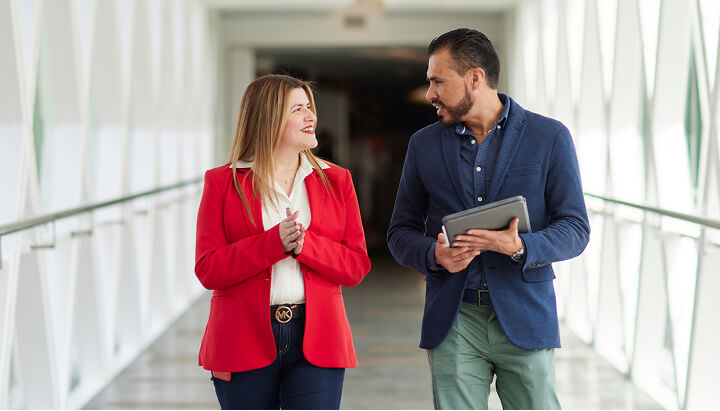 Two Colgate employees having conversation while walking through modern office hallway, showcasing culture.